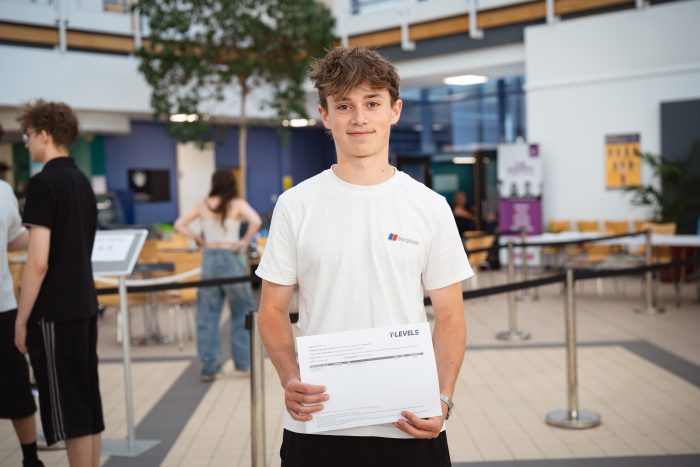 Derby College T Level student Charlie Grattidge holding a paper with his results on.