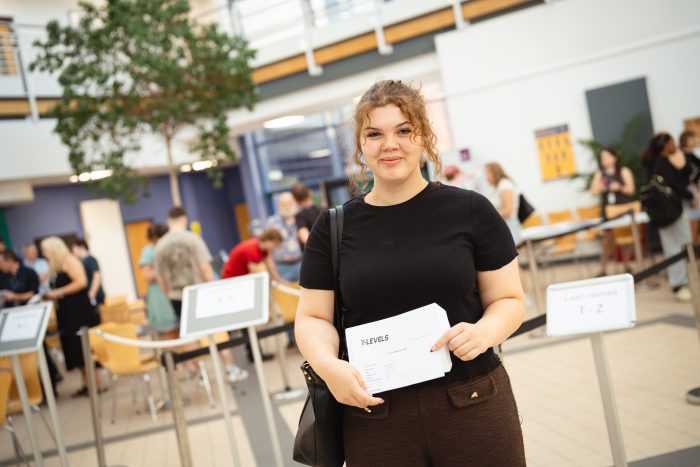 Derby College T Level student Maria Kearney holding a paper with her results on.