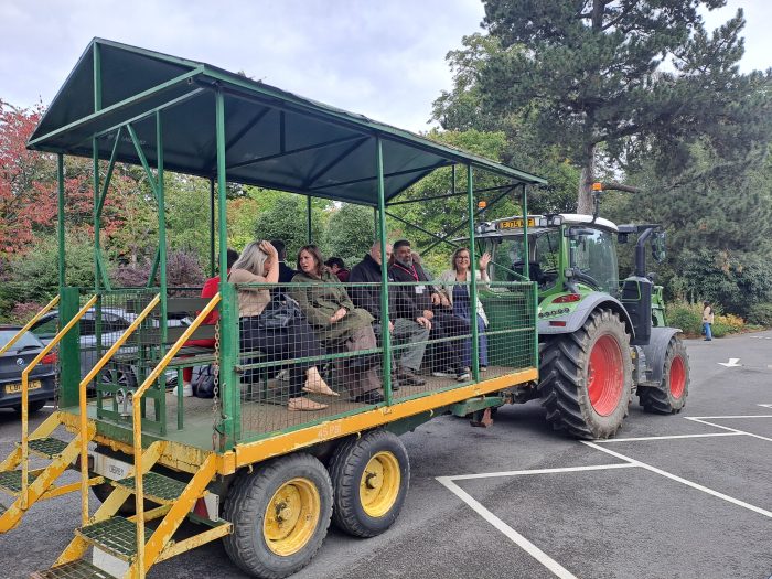 A group of people riding a green tractor at Broomfield Hall.
