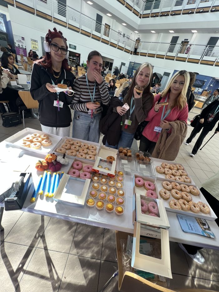 Students eating baked treats in front of a bake sale on World Mental Health Day